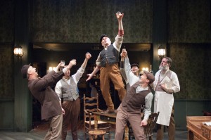 "Captain" Jack Boyle (Ron Rains, standing on table center) is declared a "Daarlin' Man" by his friends at the pub (pictured from left: James Houton, Michael Reckling, Peter Sipla, Matthew Keffer and Andy Robinson) in TimeLine Theatre's Chicago premiere production of the musical JUNO, book by Joseph Stein, music and lyrics by Marc Blitzstein, based on the play Juno and the Paycock by Sean O'Casey, directed by Nick Bowling with music direction by Doug Peck and Elizabeth Doran, presented at TimeLine Theatre, 615 W. Wellington Ave., Chicago, April 23 - July 27, 2014.