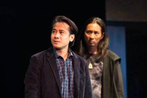 Two men standing together, one in a blazer and the other in casual attire.