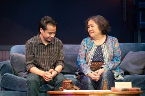 Two people sitting and sharing a warm moment on a stage.