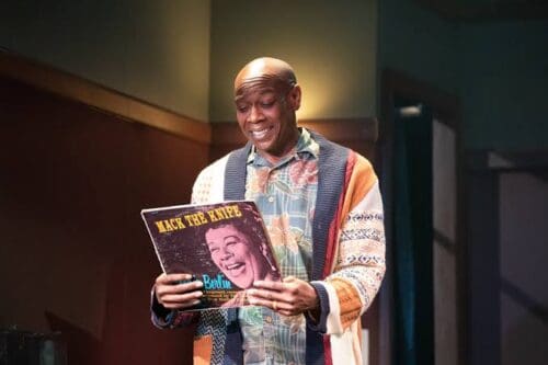 Man joyfully holding a vinyl record indoors.