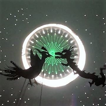 Silhouettes of birds against a glowing circular light with green patterns.