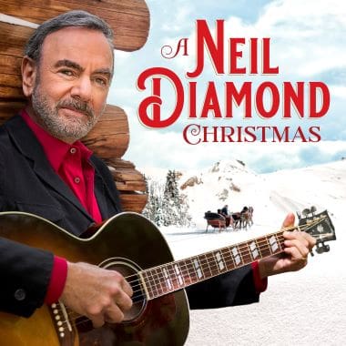 Neil Diamond holding a guitar with a Christmas-themed background.