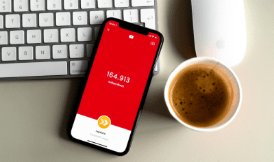 Smartphone displaying a red app screen showing a numeric value next to a coffee cup.
