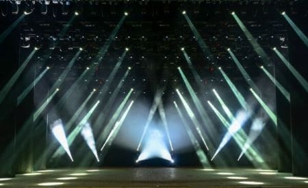 A stage with dramatic lighting beams shining in various directions.