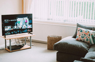 Cozy living room with a TV, gray couch, and a basket by the window.