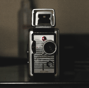 Vintage camera with a classic flash attachment against a dark background.