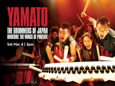 Japanese taiko drummers performing energetically with traditional drums.