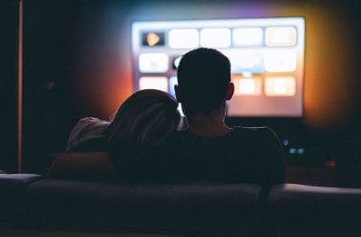 A couple watching a movie on a large screen in a dimly lit room.