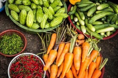 Fresh carrots, cucumbers, and chili peppers displayed at a market.