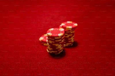 Stack of red poker chips on a red felt table.