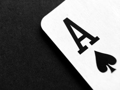 Close-up of an Ace of Spades playing card on a black background.