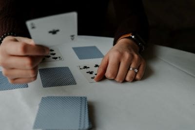 Person placing playing cards on a table with a focused hand gesture.