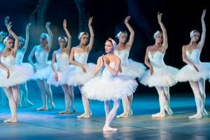 Ballet dancers performing on stage in white tutus.