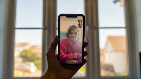 Person video calling a smiling woman on a smartphone indoors.
