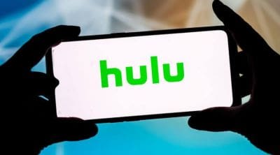 A person holding a phone displaying the Hulu logo.