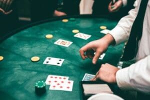 People playing a card game with poker chips on a green table.