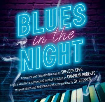 Neon sign reading 'BLUES in the NIGHT' glowing against a brick wall.