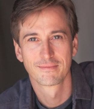 Portrait of a man with light brown hair and blue eyes.