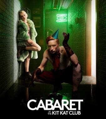 Two performers in a dimly lit alley with neon green lighting.