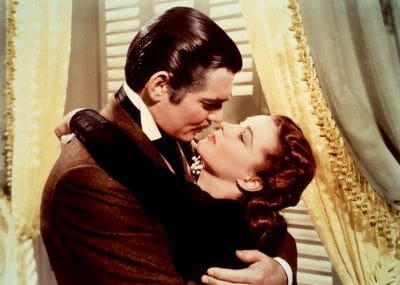 A romantic embrace and kiss between a man and a woman in vintage attire.