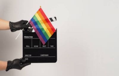 A film clapperboard with a rainbow pride flag attached to it.