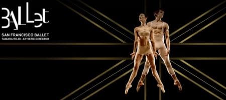 Two ballet dancers performing a synchronized leap against a dark geometric background.