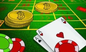 Bitcoin coins, poker chips, and playing cards on a green poker table.