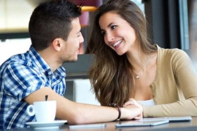 A smiling couple enjoying a conversation at a cafe.
