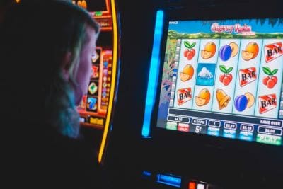 Person playing a fruit-themed slot machine in a casino.
