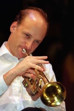 Man playing trumpet with focused expression.