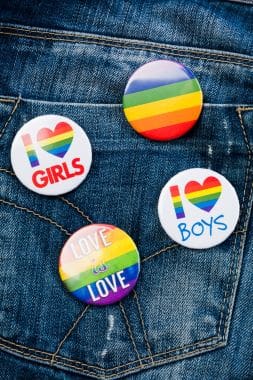 Colorful LGBTQ+ pride pins with inclusive messages on denim.