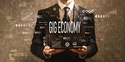 Businessman holding a transparent tablet displaying 'Gig Economy' with digital icons.
