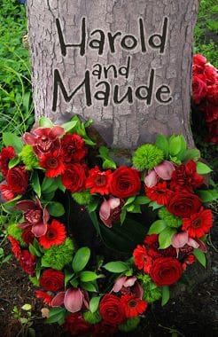 Floral wreath with red roses on a memorial plaque.