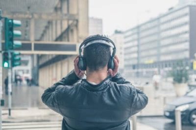 Person wearing headphones looking at urban buildings outdoors.