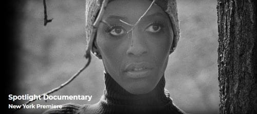 Black and white portrait of a woman with intense eyes and intricate headpiece.