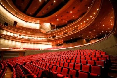 Luxurious empty theater with red seats and elegant balconies.