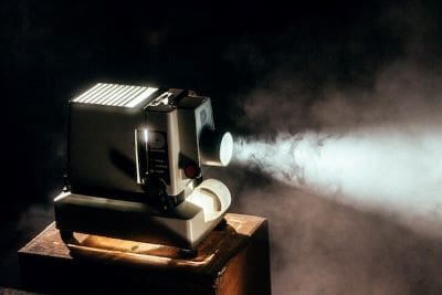 Vintage film projector casting light in a dark room.