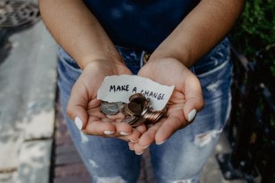 Hands holding coins and a paper saying 'Make a Change'.