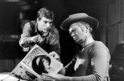 Two men intently looking at a photograph in black and white.