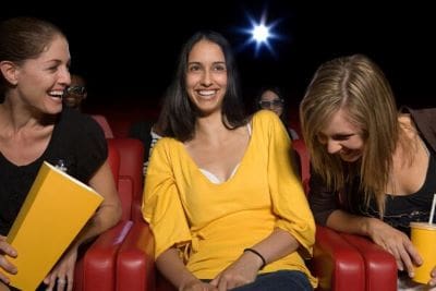Two women smiling and enjoying themselves in a dark theater.