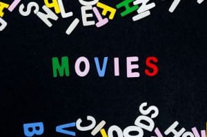 Colorful letters spelling 'MOVIES' on a black background with scattered letters around.