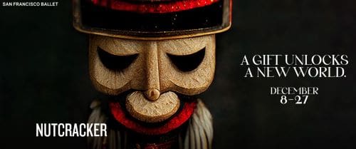 Close-up of a wooden mask with a somber expression and red accents.