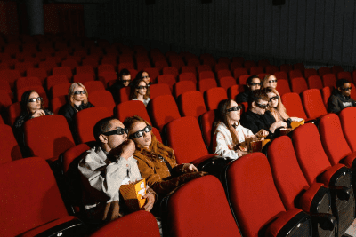 Audience wearing 3D glasses watching a movie in a theater.
