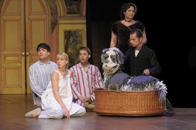 Actors performing a scene with a puppet on stage.