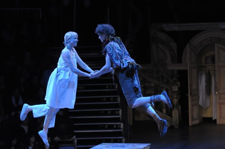 Two actors performing an intense scene on stage, one floating mid-air.