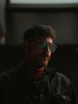 Portrait of a man wearing sunglasses in low light.