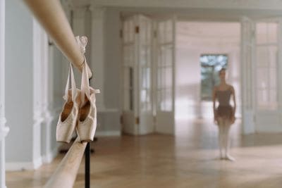 Ballet shoes hanging from a barre in a dance studio.