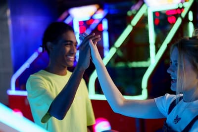 Two people exchanging a joyful high-five in a vibrant arcade setting.