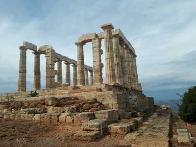 Ancient Greek temple ruins under a cloudy sky.