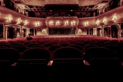 Interior view of an ornate, vintage theater with red seats and a grand stage.